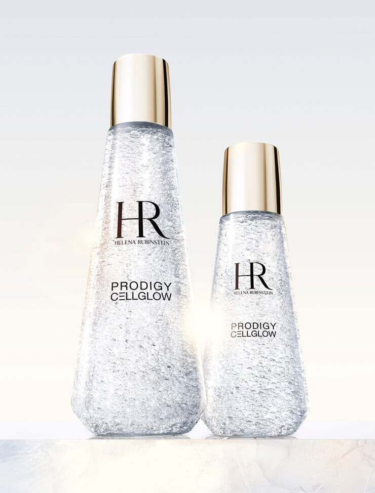  Zwei transparente Helena Rubinstein Prodigy Cellglow Serumflaschen, eine große und eine kleine, gefullt mit hydratisierenden Blaschen und goldenen Kappen, auf hellem Hintergrund.