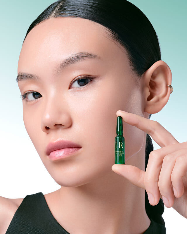 Model, das eine einzelne grune Powercell Skinmunity EXO-Ampulle in der Hand halt.