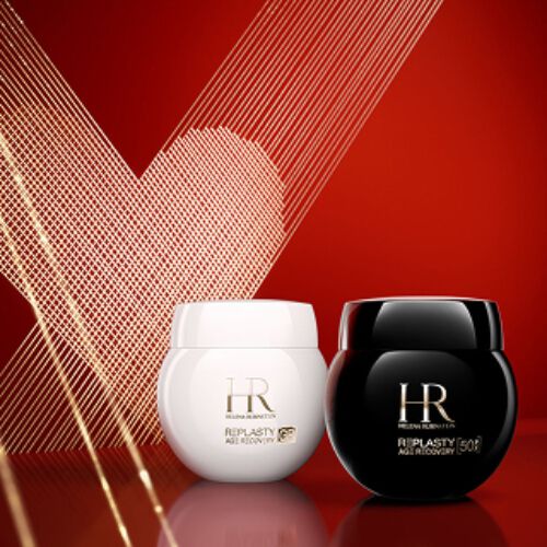 Produktfoto der Helena Rubinstein Re-Plasty Age Recovery Tagescreme in einem glanzenden weißen Tiegel und der Re-Plasty Age Recovery Nachtcreme in einem glanzenden schwarzen Tiegel. Die Tiegel stehen nebeneinander auf einer reflektierenden roten Oberflache vor einem tiefroten Hintergrund mit einem goldenen Line-Art-Herz.​