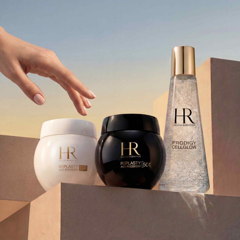 Helena Rubinstein Prodigy Cellglow Serumflasche (klar, Blaschen) und Re-Plasty Cremetiegel (schwarz). Auf einem texturierten, leuchtenden weißen Hintergrund platziert, symbolisiert Eleganz und Pflegeeffizienz.